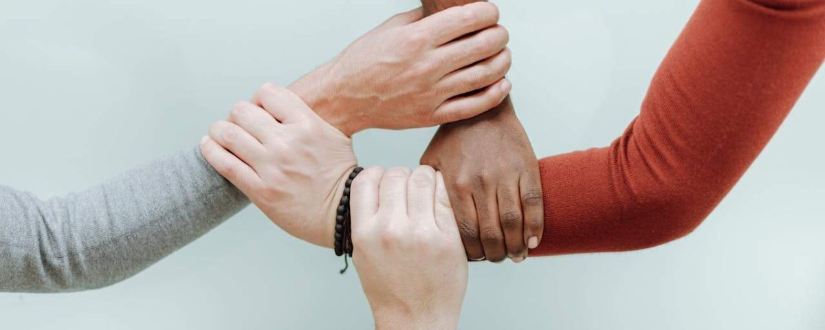 Close-up of diverse hands holding each other in a symbol of unity and togetherness.